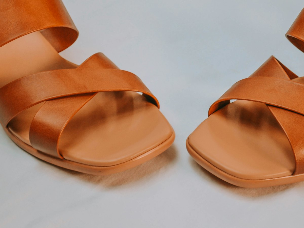 Tan leather sandals on a pale grey background.