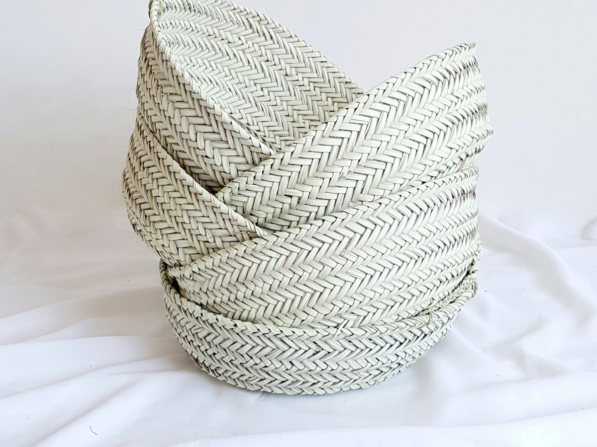 Woven straw bowls stacked on a white cloth.
