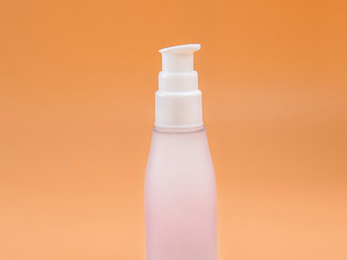 A pump bottle of body lotion on a peach background.